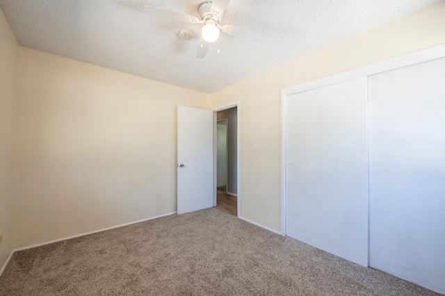 unfurnished bedroom featuring a closet, ceiling fan, a textured ceiling, and carpet floors