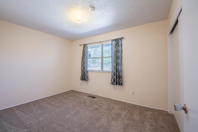 carpeted empty room featuring a textured ceiling