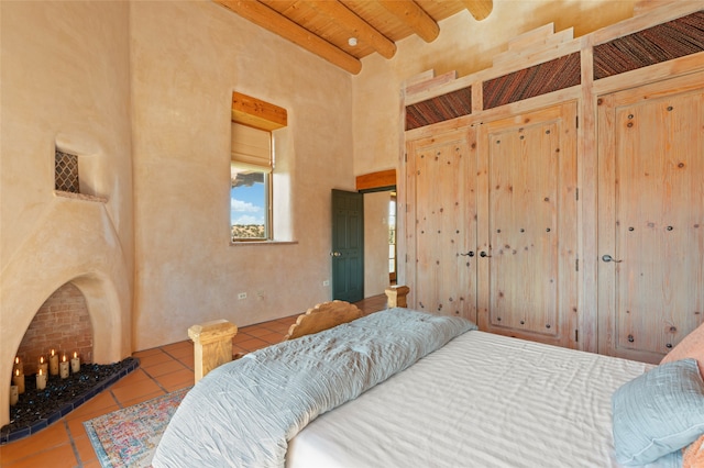 bedroom featuring beam ceiling, tile patterned flooring, a high ceiling, and wooden ceiling