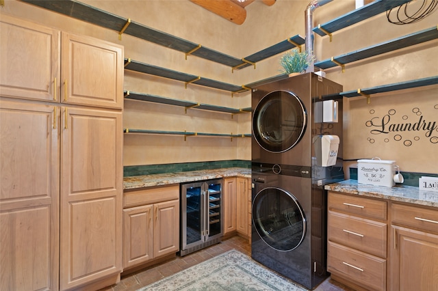 laundry room featuring cabinets, light tile patterned flooring, stacked washer / drying machine, and beverage cooler