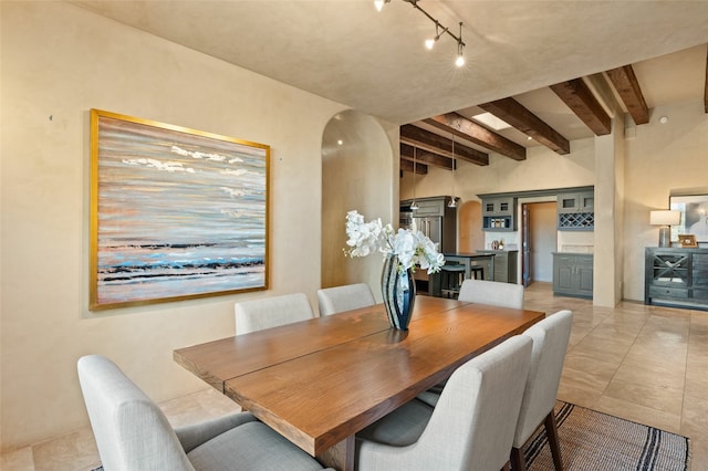 dining area featuring beam ceiling and light tile patterned floors