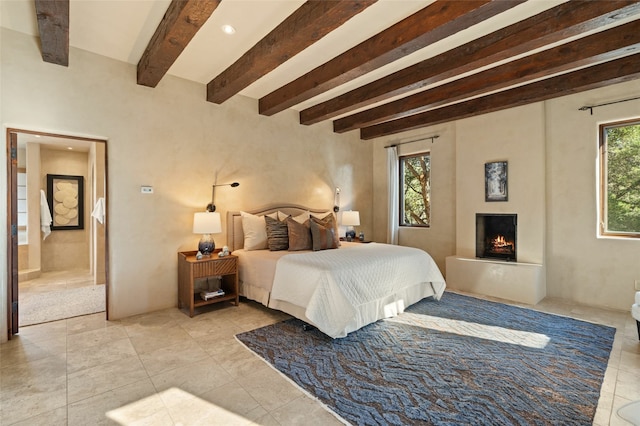 tiled bedroom with ensuite bathroom and beamed ceiling