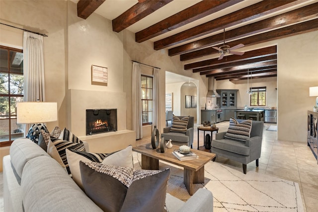 living room featuring beam ceiling, a healthy amount of sunlight, ceiling fan, and light tile patterned floors