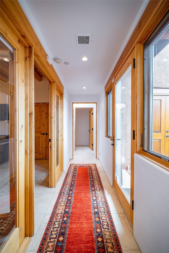 hallway with a healthy amount of sunlight and light tile patterned floors