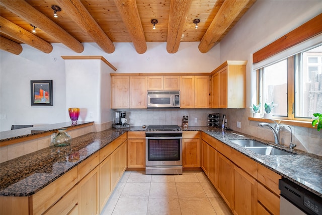 kitchen with stainless steel appliances, tasteful backsplash, sink, and dark stone counters