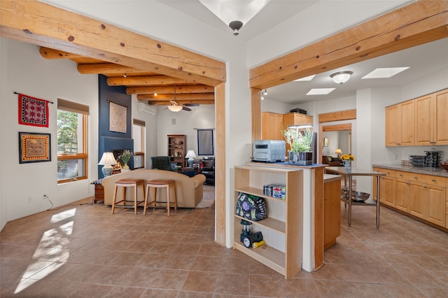 kitchen with light brown cabinets, a kitchen bar, beamed ceiling, and tile patterned flooring