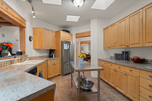 kitchen featuring high end refrigerator, light brown cabinetry, sink, and a skylight