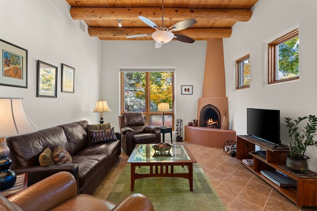 living room with a large fireplace, beam ceiling, ceiling fan, and wooden ceiling