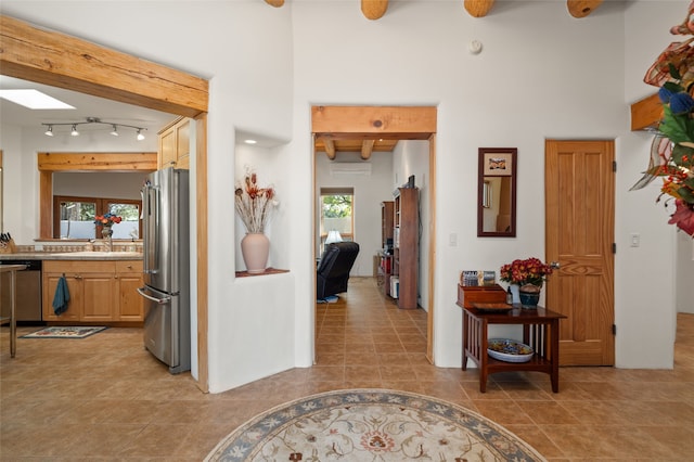 corridor featuring beamed ceiling, a wealth of natural light, sink, and tile patterned floors