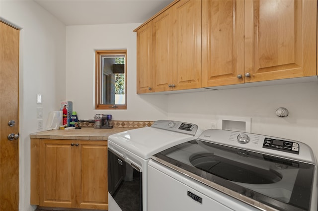 washroom featuring washing machine and clothes dryer and cabinets