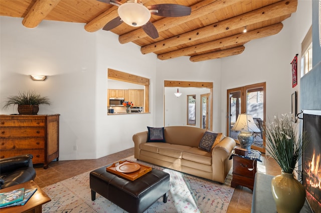 tiled living room with a high ceiling, beamed ceiling, wood ceiling, and ceiling fan