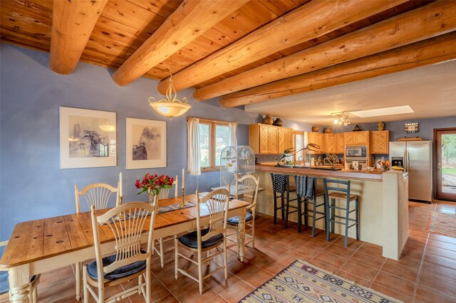 dining area with a skylight, beamed ceiling, wood ceiling, and light tile patterned floors