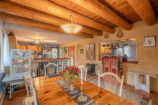 tiled dining area with beamed ceiling, rail lighting, a baseboard radiator, and wood ceiling