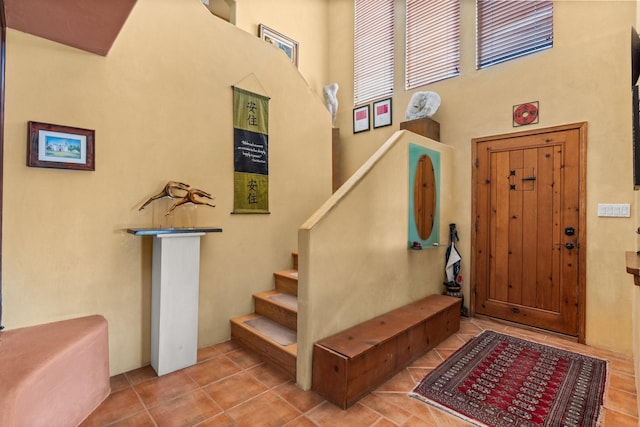tiled foyer entrance featuring stairs and a towering ceiling