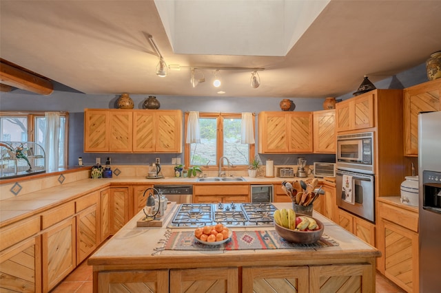 kitchen featuring light brown cabinetry, track lighting, stainless steel appliances, sink, and light tile patterned flooring