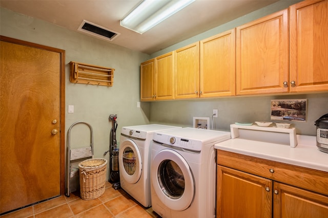 laundry room featuring washer and clothes dryer, cabinets, and light tile patterned floors