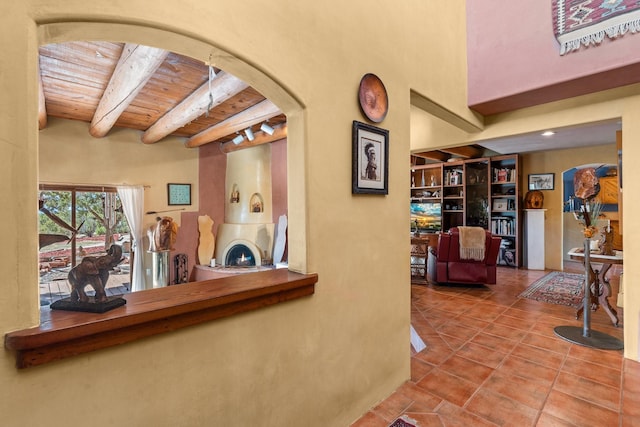 interior space with arched walkways, wood ceiling, tile patterned floors, and beamed ceiling