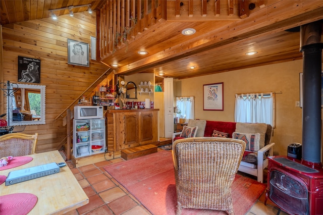 interior space featuring a wood stove, wood ceiling, a healthy amount of sunlight, and wood walls