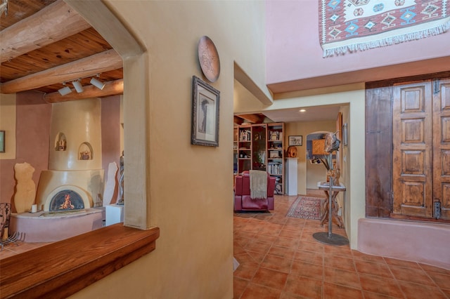 hall featuring beamed ceiling, light tile patterned flooring, and wood ceiling