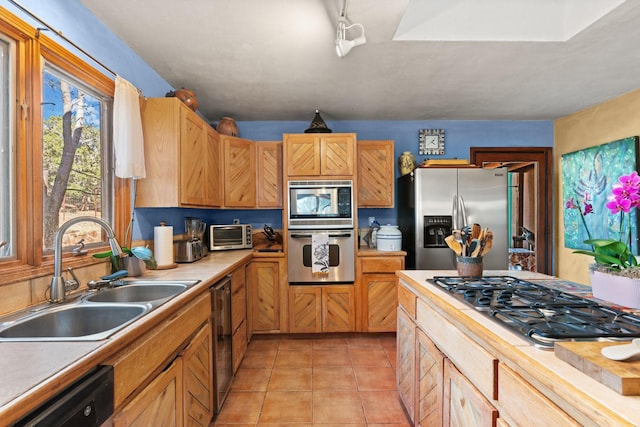 kitchen featuring appliances with stainless steel finishes, a sink, light countertops, light tile patterned floors, and a toaster