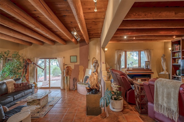 tiled living room with beam ceiling, a stone fireplace, rail lighting, and wood ceiling