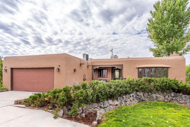 pueblo revival-style home featuring a garage