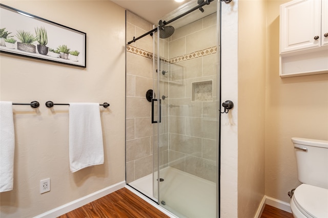 bathroom with a shower with door, toilet, and hardwood / wood-style flooring