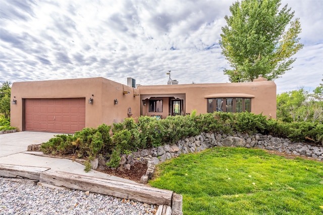 pueblo revival-style home with a front yard and a garage