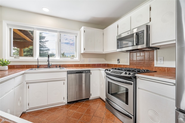 kitchen featuring tile countertops, stainless steel appliances, sink, and white cabinets