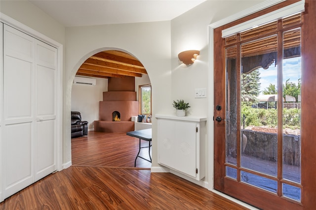 entrance foyer with vaulted ceiling with beams, wood-type flooring, and a wall mounted air conditioner