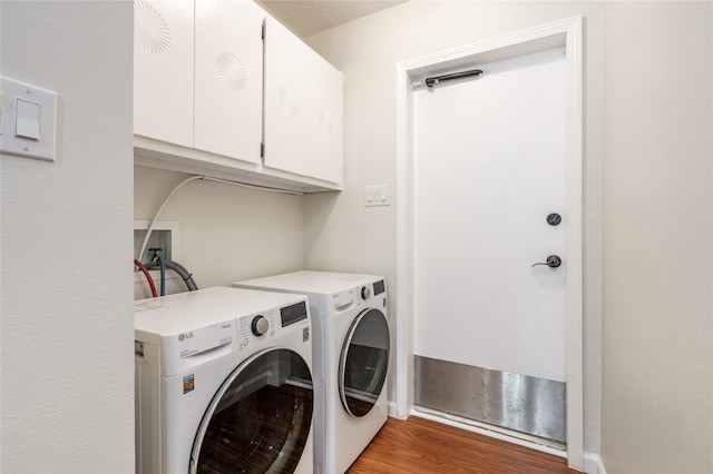 washroom with dark wood-type flooring, cabinets, and washing machine and clothes dryer