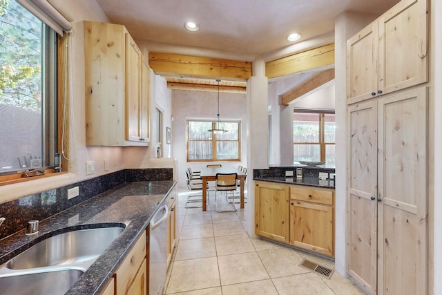 kitchen with light brown cabinetry, pendant lighting, stainless steel dishwasher, and sink