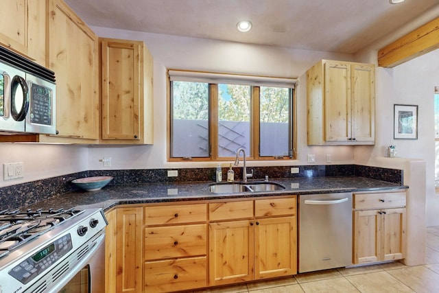 kitchen featuring appliances with stainless steel finishes, light brown cabinetry, dark stone counters, sink, and light tile patterned flooring