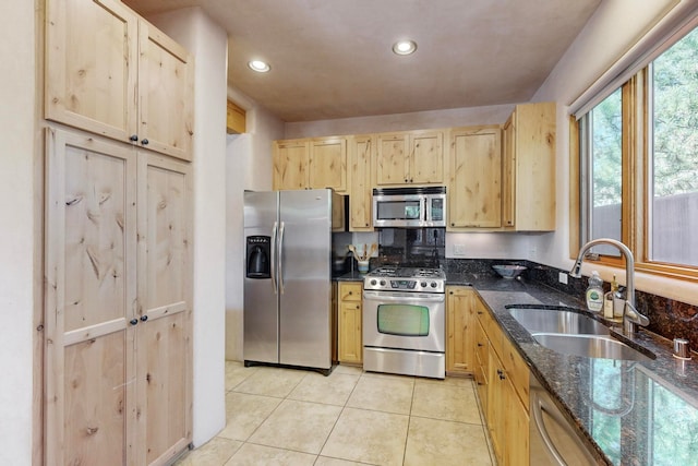 kitchen featuring light tile patterned flooring, dark stone countertops, sink, and appliances with stainless steel finishes