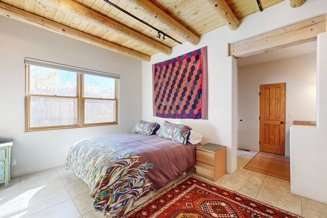 bedroom featuring beam ceiling, light tile patterned floors, and wooden ceiling