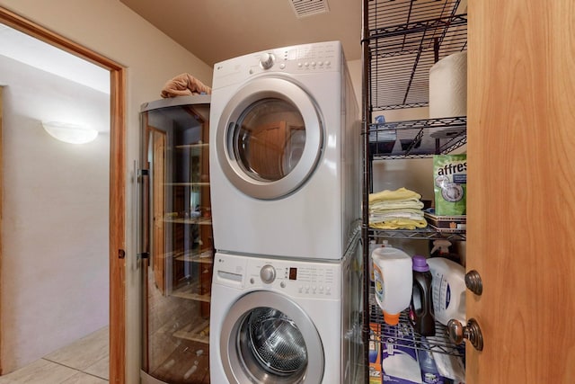 laundry area with light tile patterned floors and stacked washer and clothes dryer