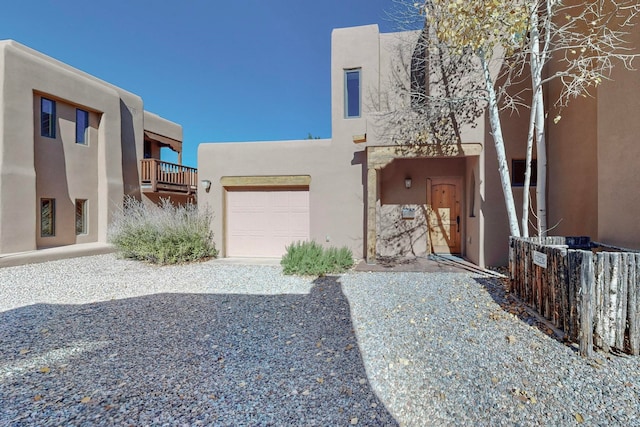 pueblo-style home featuring a balcony and a garage