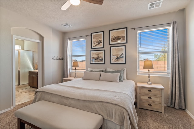 carpeted bedroom with connected bathroom, a textured ceiling, and ceiling fan