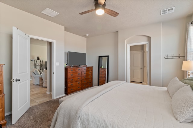 bedroom with light carpet, a textured ceiling, and ceiling fan