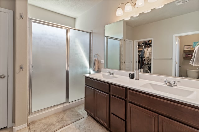 bathroom featuring vanity, a textured ceiling, toilet, and walk in shower