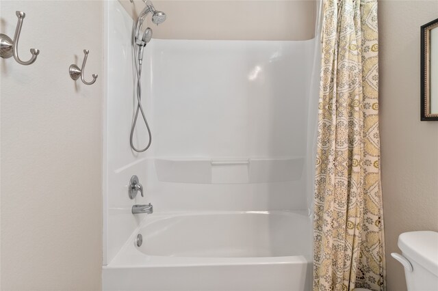 bathroom with toilet and shower / bath combo with shower curtain