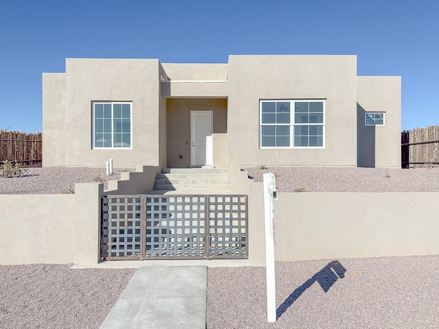 pueblo revival-style home featuring stucco siding and fence