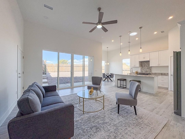 living room with visible vents, light wood-style flooring, a high ceiling, recessed lighting, and ceiling fan