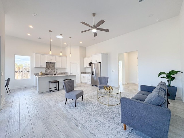 living area featuring visible vents, baseboards, recessed lighting, ceiling fan, and light wood-type flooring