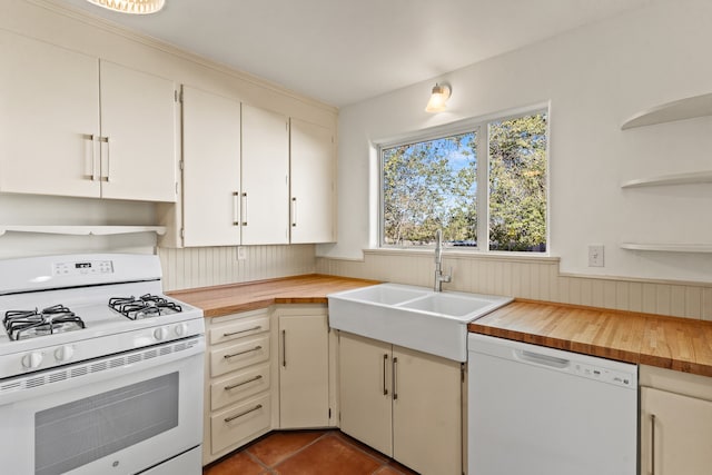 kitchen featuring white appliances, wooden counters, white cabinets, sink, and dark tile patterned floors