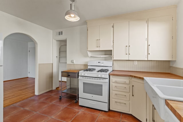 kitchen with wood-type flooring, decorative light fixtures, white gas range, and sink