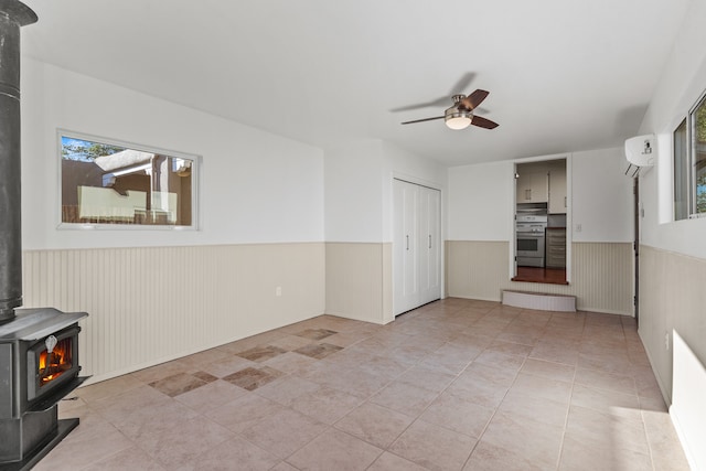 tiled empty room with ceiling fan, a wood stove, and a wall mounted AC