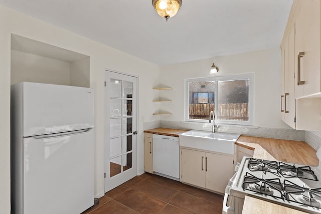 kitchen with white appliances, dark tile patterned floors, and sink