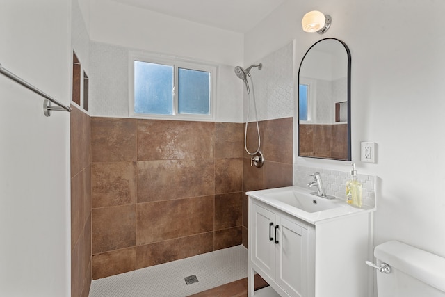 bathroom featuring decorative backsplash, toilet, vanity, and tiled shower