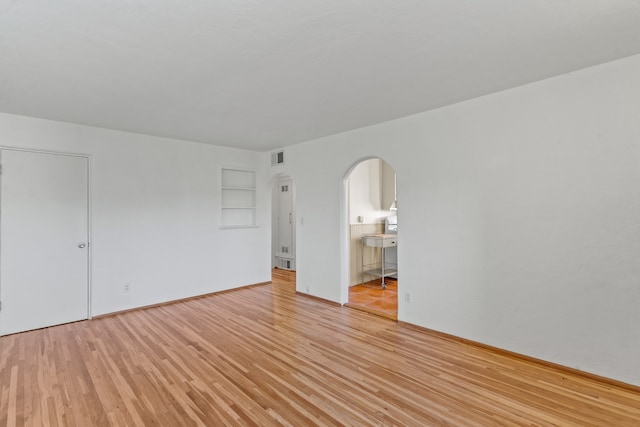 empty room featuring built in shelves and light wood-type flooring